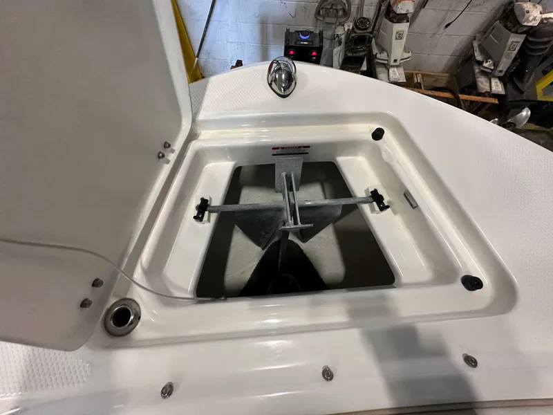 Slide: The Image of 2019 Robalo R207 Dual Console anchor compartment, open lid, indoor setting. - 19