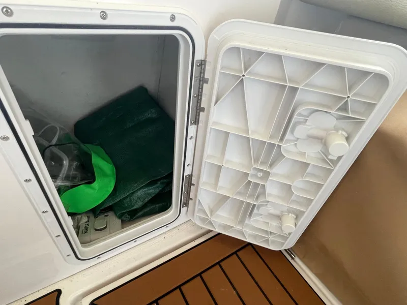 Slide: The Image of Open storage compartment on 2023 Ranger Tugs R-25 boat with green items inside. - 11