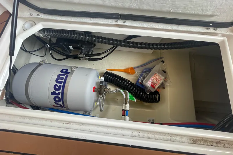 Slide: The Image of 2023 Ranger Tugs R-25 storage compartment with water heater and accessories. - 15