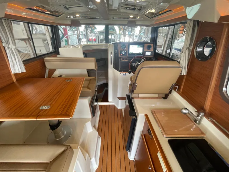 Slide: The Image of Interior of 2023 Ranger Tugs R-25 boat, featuring helm, seating, and kitchenette. - 17