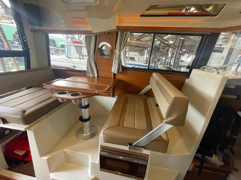 Slide: The Image of 2023 Ranger Tugs R-25 interior with brown seating and wooden table. - 19
