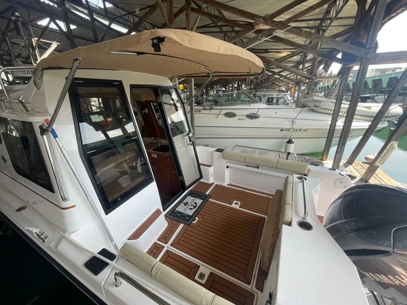 Slide: The Image of 2023 Ranger Tugs R-25 boat with spacious deck and canopy in marina setting. - 2