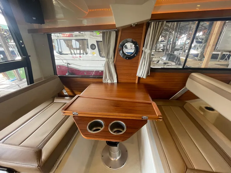Slide: The Image of Interior of 2023 Ranger Tugs R-25 with wood table and beige seating. - 21