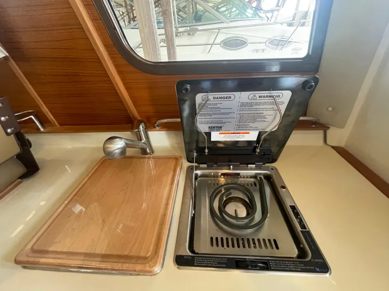 Slide: The Image of 2023 Ranger Tugs R-25 kitchen with stove and cutting board. - 23