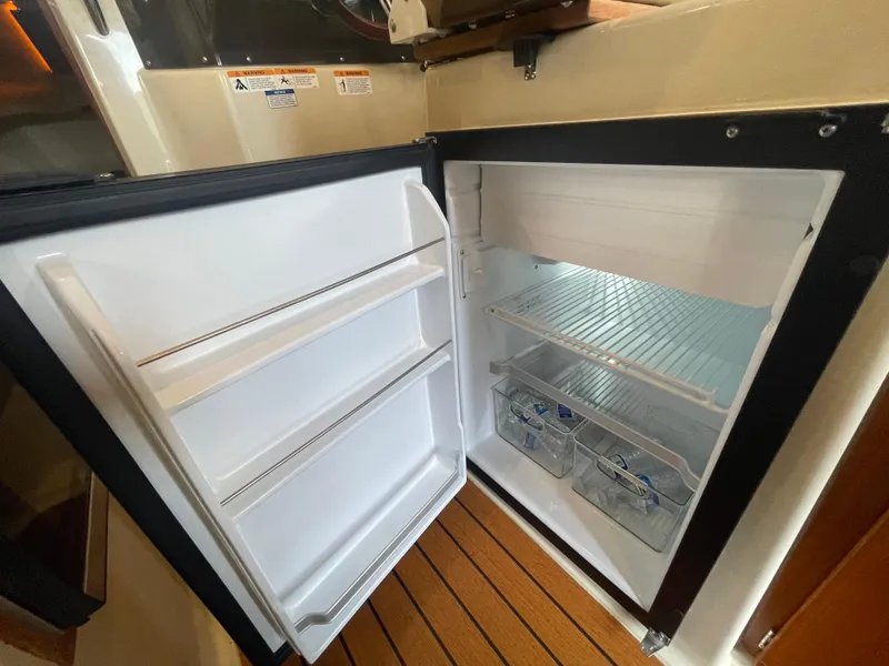 Slide: The Image of 2023 Ranger Tugs R-25 boat interior with open refrigerator, showcasing storage space. - 25