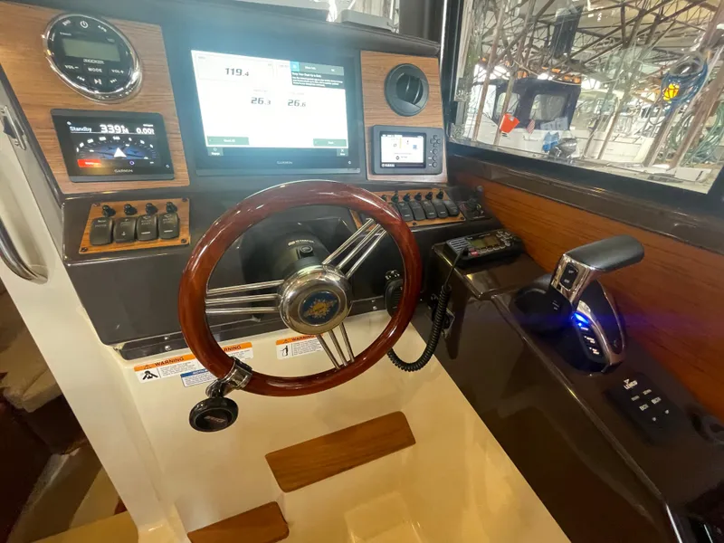 Slide: The Image of 2023 Ranger Tugs R-25 helm with wooden steering wheel and modern navigation controls. - 27