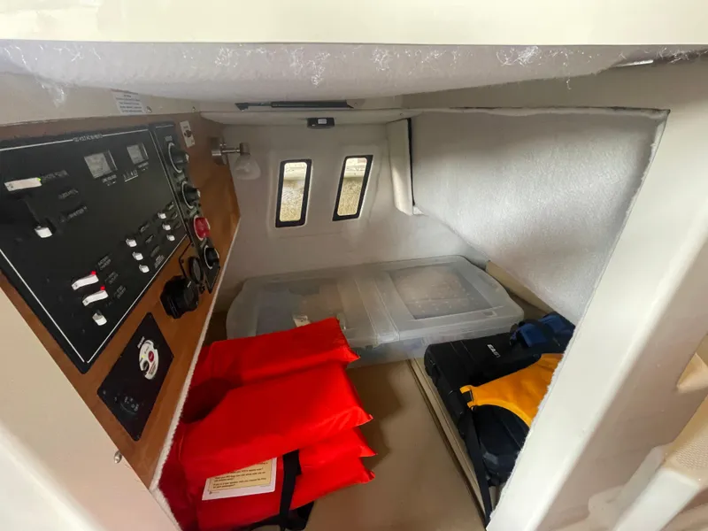 Slide: The Image of 2023 Ranger Tugs R-25 cabin interior with control panel, life jackets, and storage containers. - 32