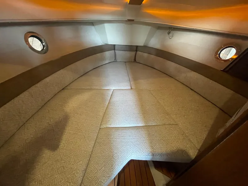 Slide: The Image of 2023 Ranger Tugs R-25 interior cabin with cushioned seating and porthole windows. - 38