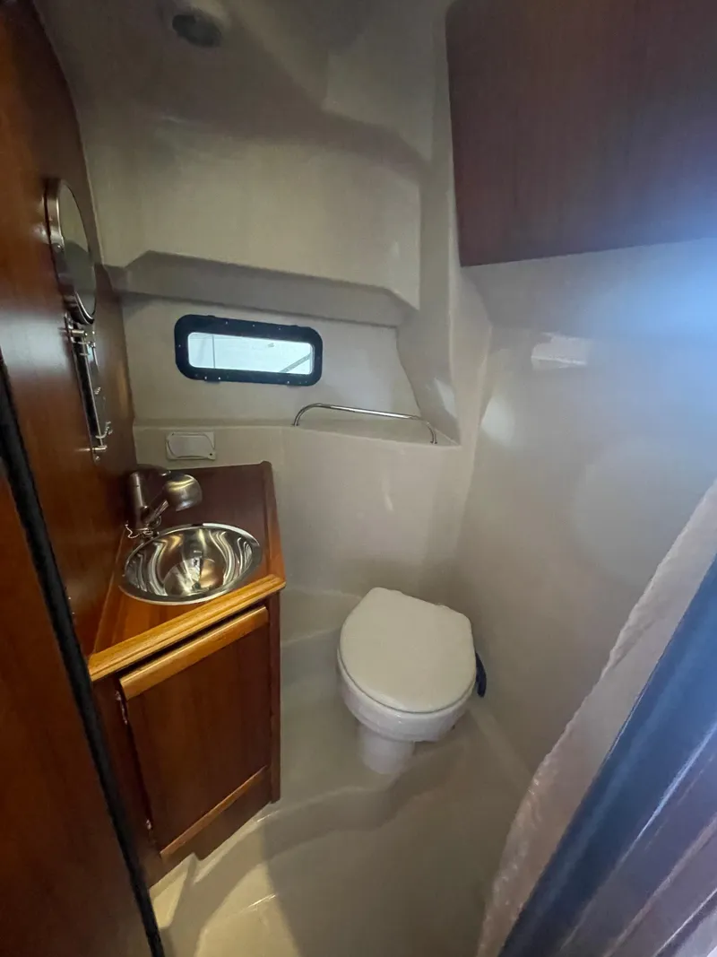 Slide: The Image of 2023 Ranger Tugs R-25 boat bathroom with sink, toilet, and window. - 43