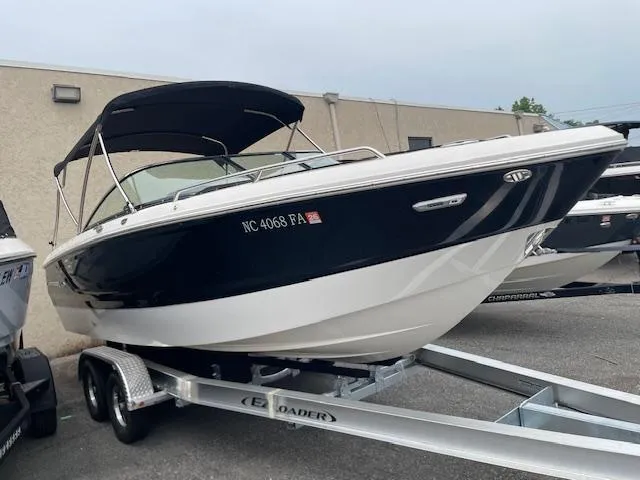 Slide: The Image of 2023 Chaparral 247 SSX boat on trailer, black and white design, parked outdoors. - 2