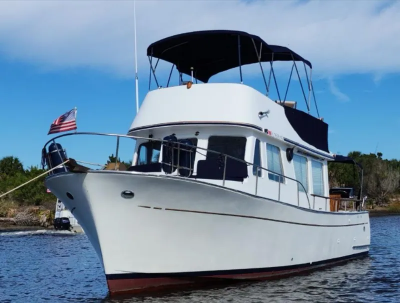 Slide: The Image of 1973 CHB Trawler boat on water with American flag, blue sky background. - 0