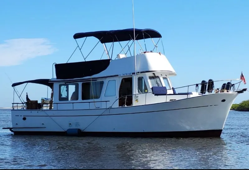 Slide: The Image of 1973 CHB Trawler boat on calm water under clear blue sky. - 1