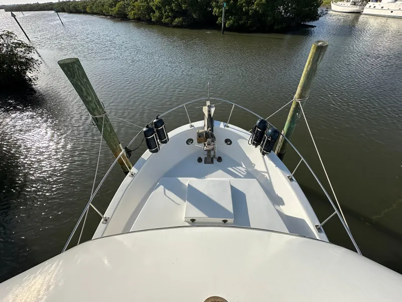 Slide: The Image of 1973 CHB Trawler boat docked on calm water, surrounded by lush greenery. - 11