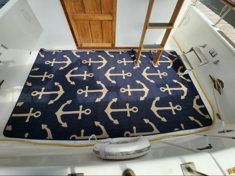 Slide: The Image of 1973 CHB Trawler deck with anchor-patterned rug and wooden ladder. - 12