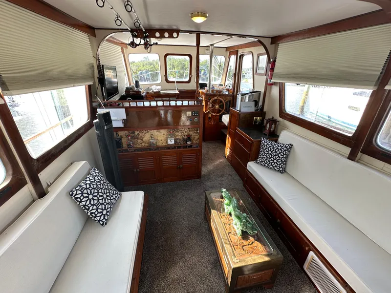 Slide: The Image of 1973 CHB Trawler interior with white seating, wooden accents, and nautical decor. - 14
