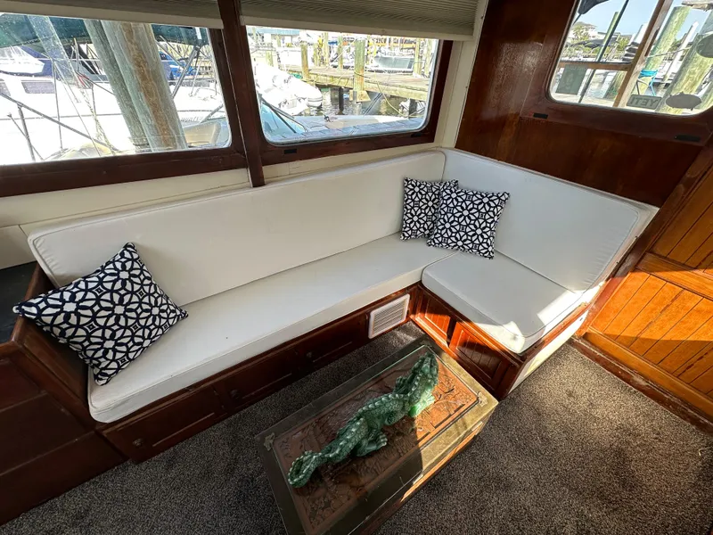 Slide: The Image of 1973 CHB Trawler interior with white seating, patterned pillows, and a decorative table. - 16
