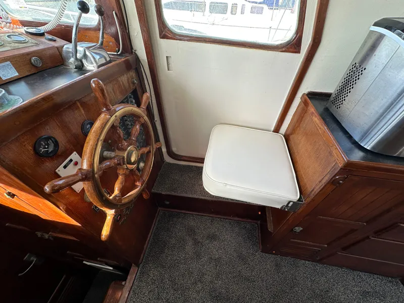 Slide: The Image of 1973 CHB Trawler helm with wooden wheel, cushioned seat, and control panel. - 18