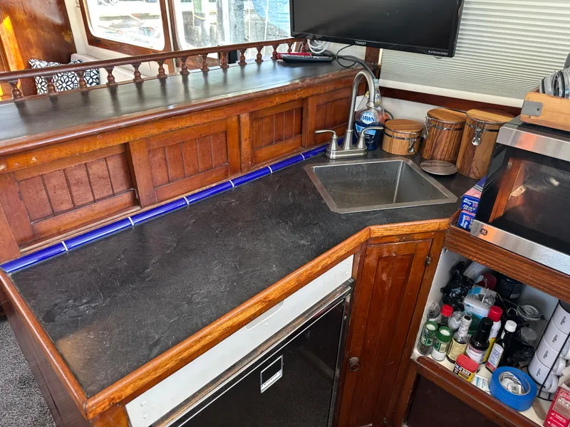 Slide: The Image of 1973 CHB Trawler kitchen with wooden cabinetry, sink, and countertop. - 23
