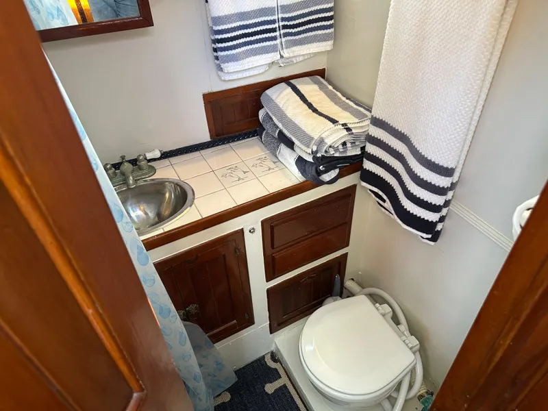 Slide: The Image of 1973 CHB Trawler bathroom with sink, toilet, and striped towels. - 25
