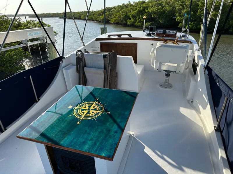 Slide: The Image of 1973 CHB Trawler boat deck with compass table, overlooking serene river and lush greenery. - 6