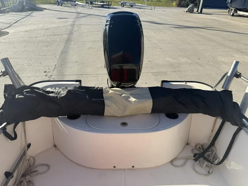 Slide: The Image of 2007 Boston Whaler 150 Montauk boat with covered outboard motor, docked on concrete. - 10