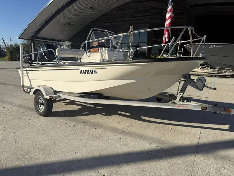 Slide: The Image of 2007 Boston Whaler 150 Montauk boat on trailer, parked outdoors with American flag. - 2