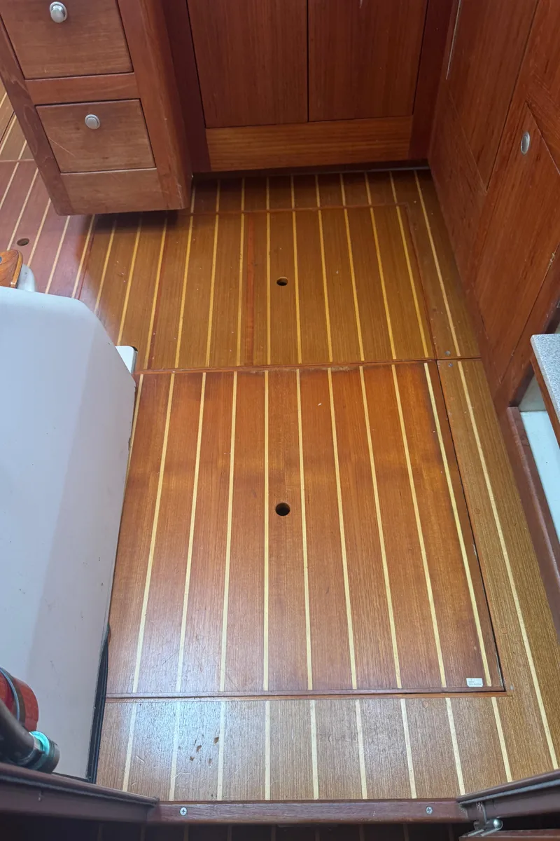 Slide: The Image of Wooden cabin floor of a 1998 Hunter 410 boat, featuring storage access panels. - 6