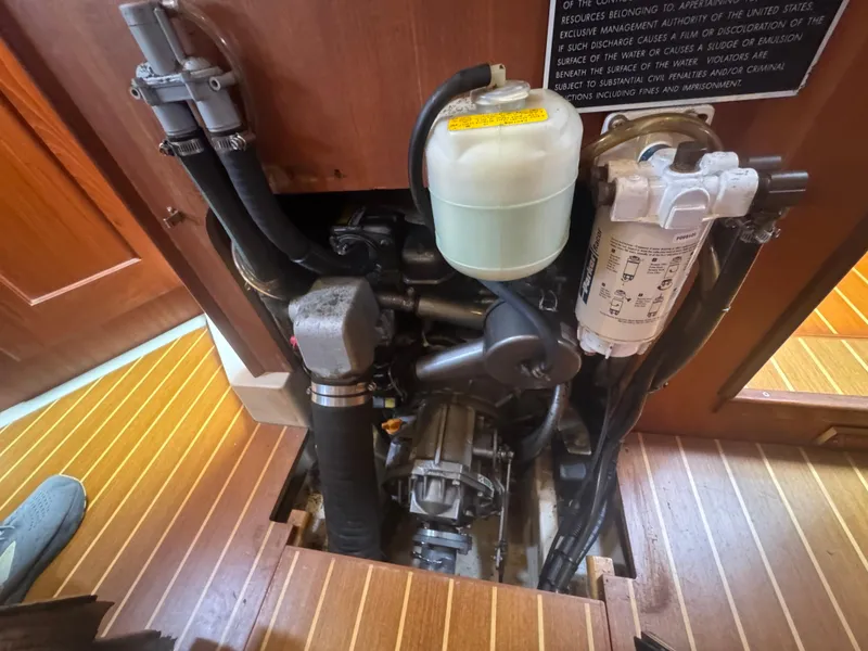 Slide: The Image of Engine compartment of a 1998 Hunter 410 sailboat, showcasing mechanical components and wooden flooring. - 7