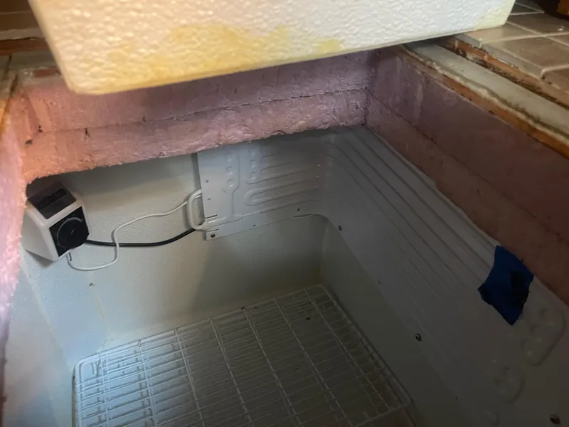 Slide: The Image of Interior of a 1976 Cheoy Lee Clipper 42 refrigerator with insulation and wiring visible. - 33