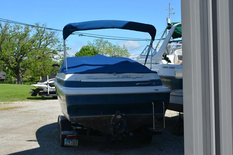Slide: The Image of 1997 Maxum 2300 SR boat with blue cover, parked on a trailer outdoors. - 3