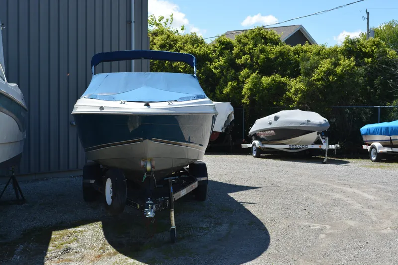 Slide: The Image of 1997 Maxum 2300 SR boat on trailer, parked outdoors near other boats. - 4