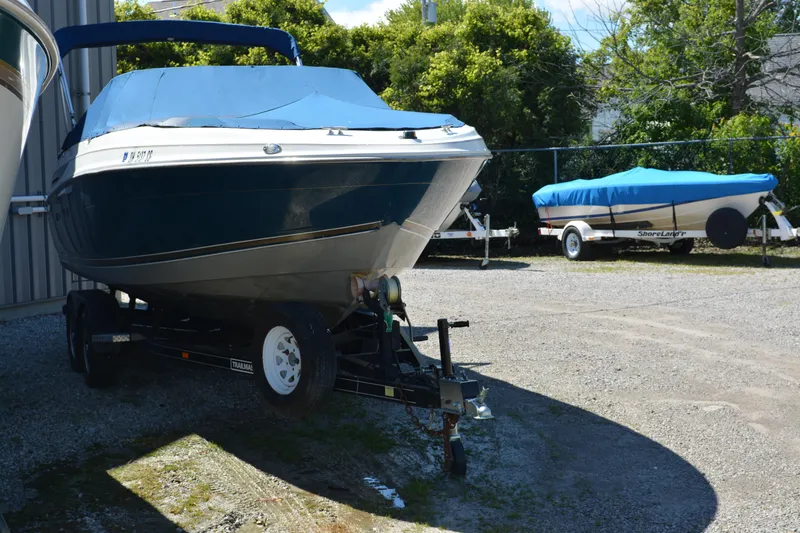 Slide: The Image of 1997 Maxum 2300 SR boat on trailer, parked outdoors with another covered boat nearby. - 5