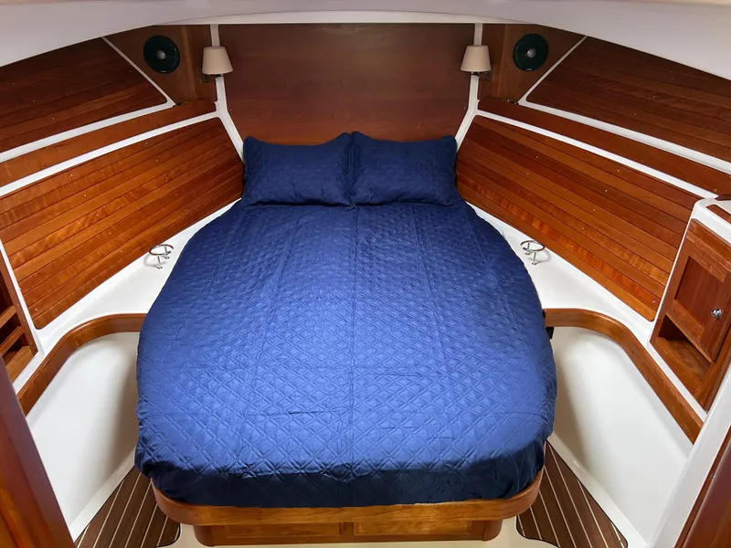 Slide: The Image of 2018 Back Cove 32 cabin interior with blue bedding and wooden accents. - 12