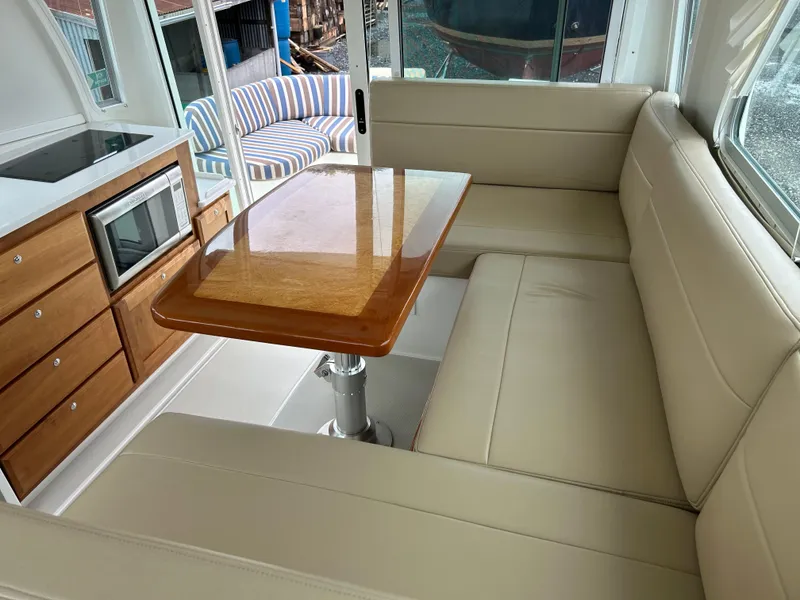 Slide: The Image of 2018 Back Cove 32 interior with beige seating, wooden table, and kitchenette. - 8
