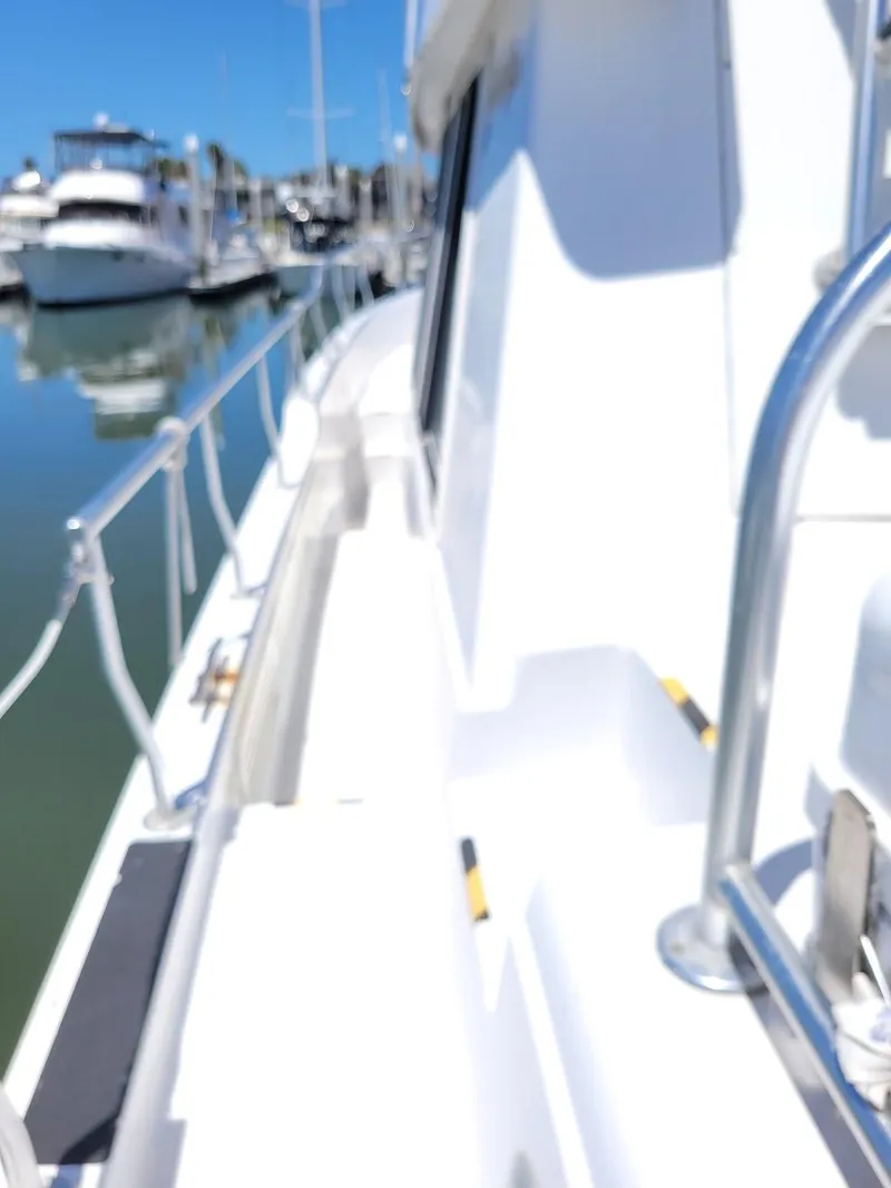 Slide: The Image of 1999 Mainship 430 Trawler docked, showcasing sleek white deck and railing. - 12