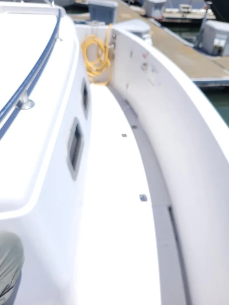 Slide: The Image of 1999 Mainship 430 Trawler deck view at marina, featuring clean white surface and dockside equipment. - 14