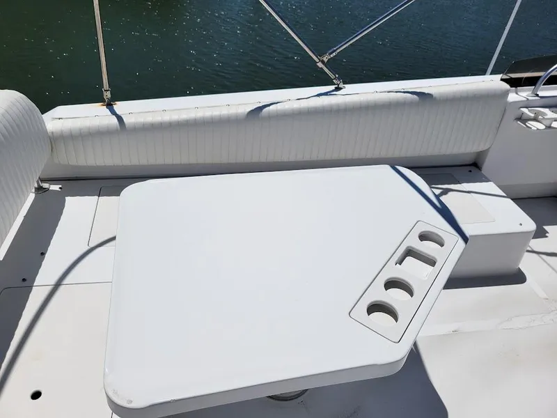 Slide: The Image of 1999 Mainship 430 Trawler deck with white table and cup holders, overlooking water. - 24