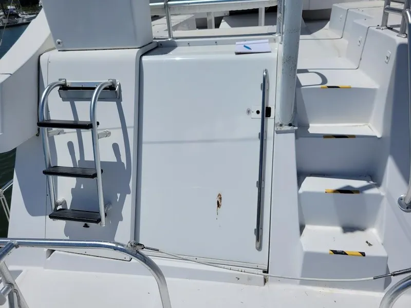 Slide: The Image of 1999 Mainship 430 Trawler deck with ladder and steps, featuring white exterior. - 26