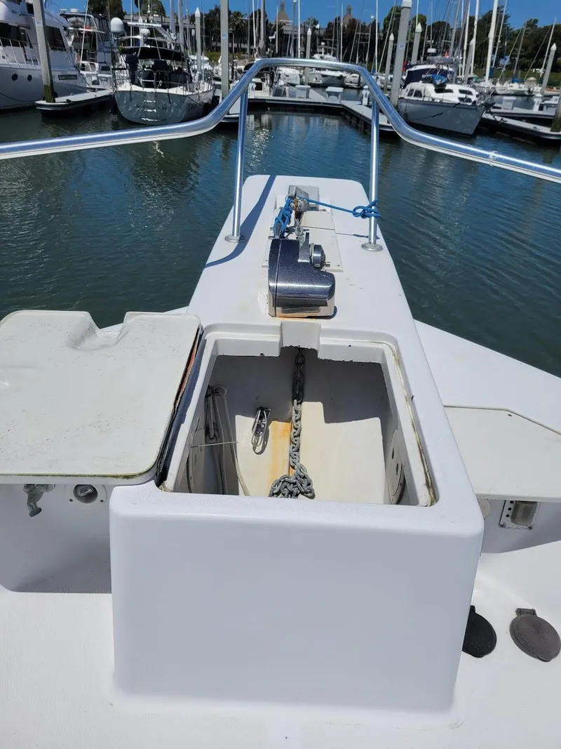Slide: The Image of 1999 Mainship 430 Trawler anchor locker, open on deck, with marina background. - 3