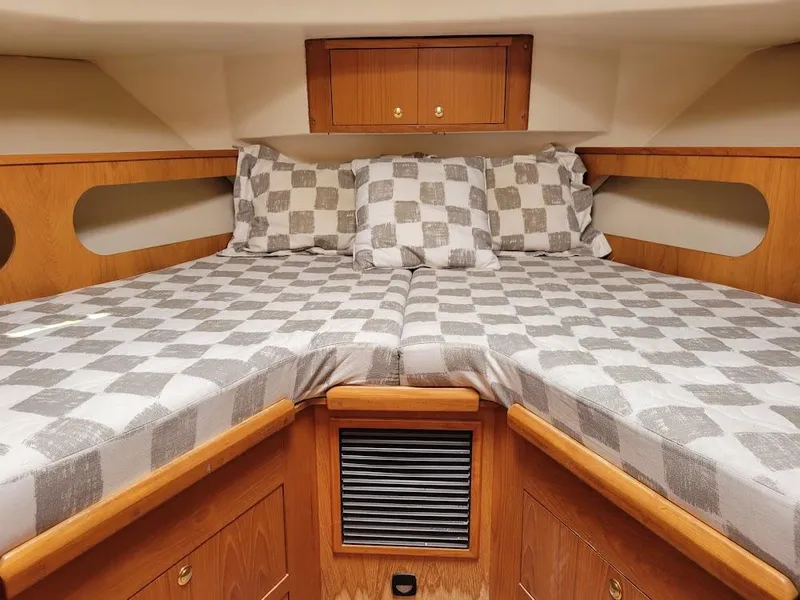 Slide: The Image of 1999 Mainship 430 Trawler cabin with checkered bedding and wooden cabinetry. - 36