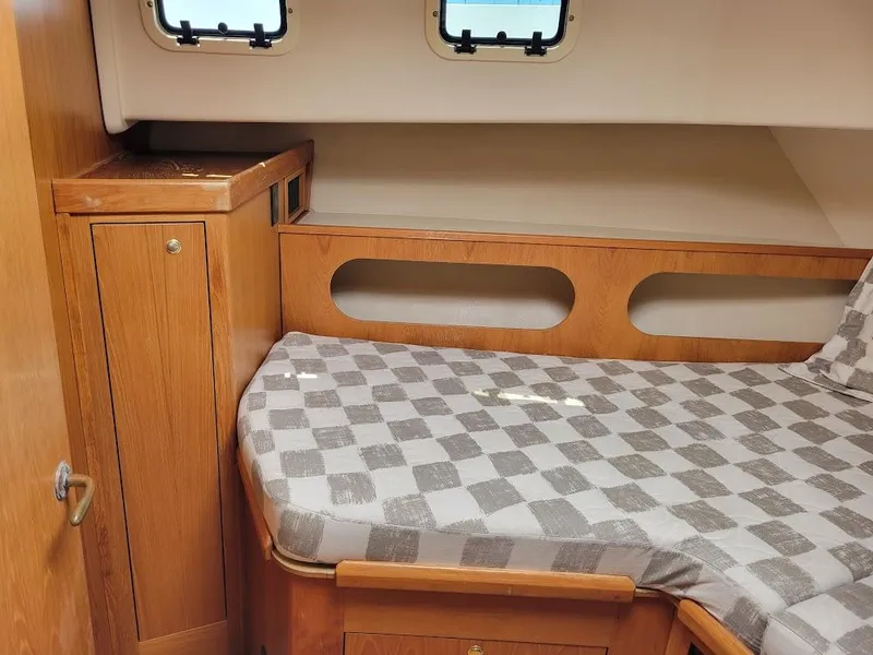 Slide: The Image of 1999 Mainship 430 Trawler cabin with wooden interior and checkered bedding. - 37