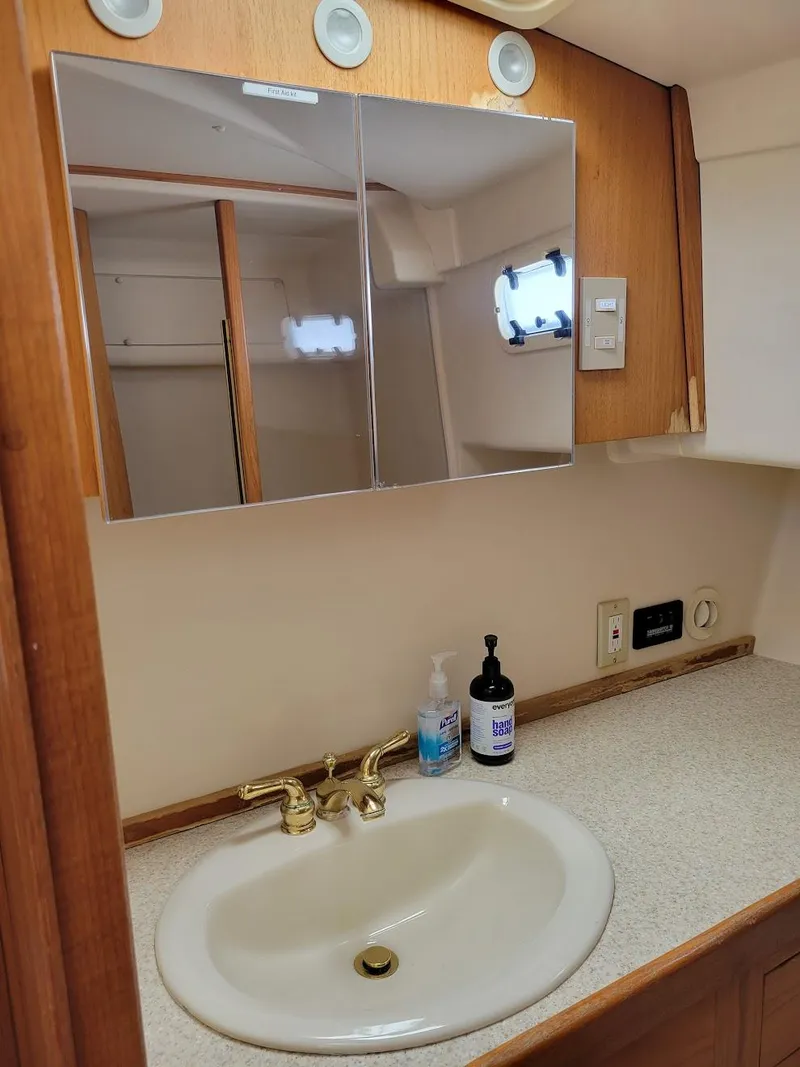 Slide: The Image of 1999 Mainship 430 Trawler bathroom with sink, mirror, and wooden cabinetry. - 41