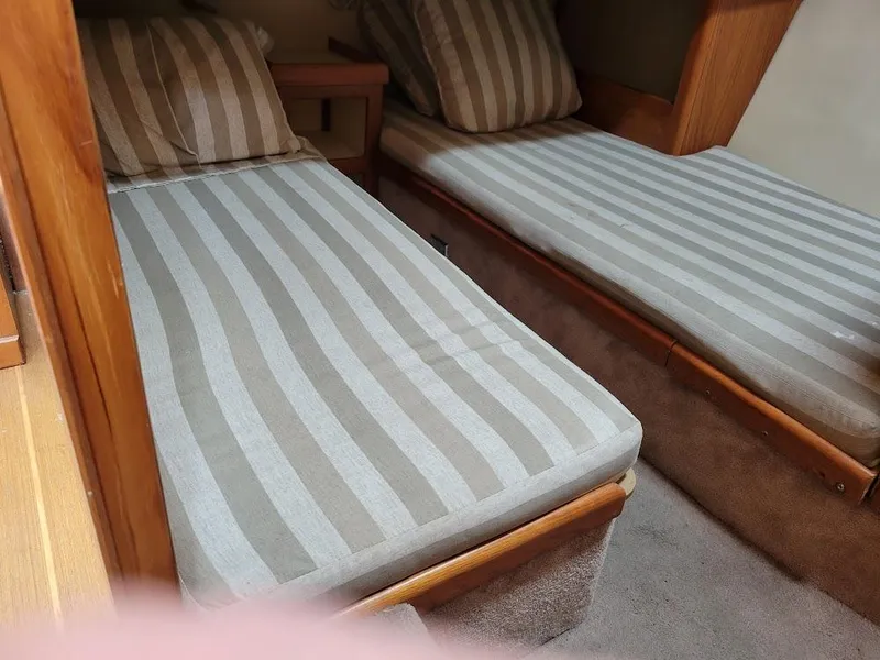 Slide: The Image of Twin beds with striped bedding in a 1999 Mainship 430 Trawler cabin. - 45