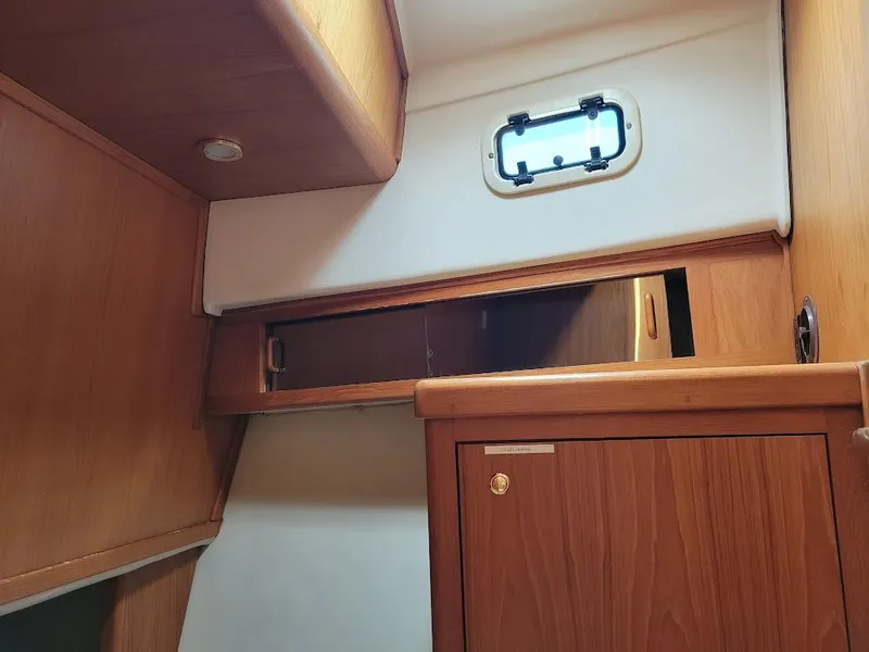 Slide: The Image of Interior cabin of 1999 Mainship 430 Trawler with wooden cabinetry and small window. - 46