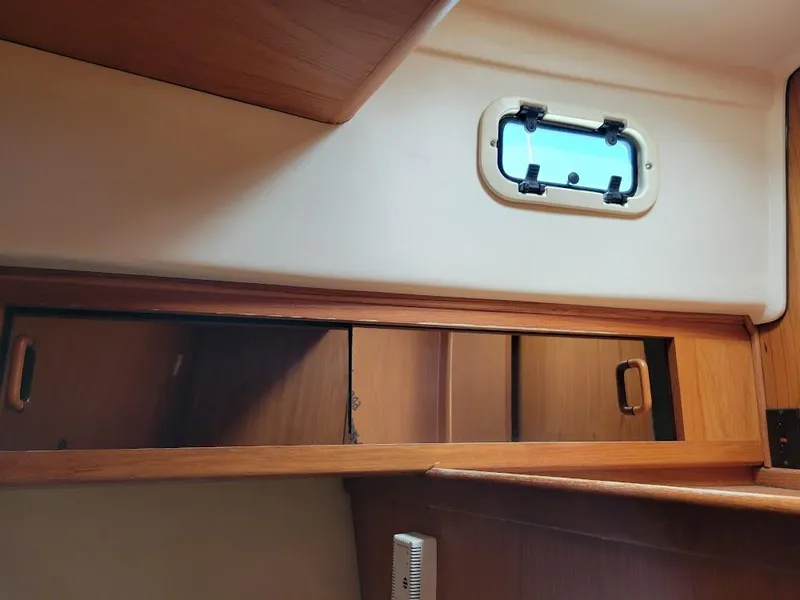Slide: The Image of Interior of 1999 Mainship 430 Trawler with wooden cabinets and a small window. - 47