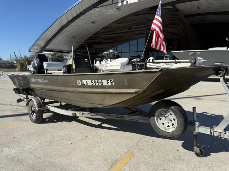 Slide: The Image of 2000 War Eagle 18 boat on trailer with American flag, parked outdoors. - 1