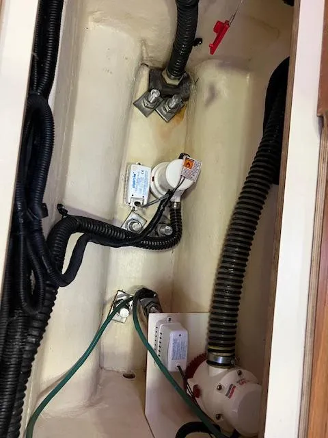 Slide: The Image of 2006 Hunter 44 Deck Salon bilge area with wiring and pump components. - 16