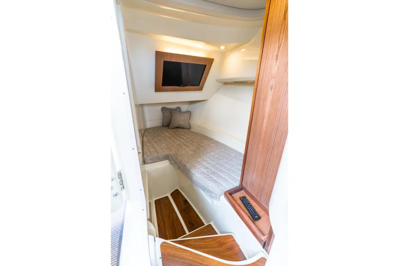 Slide: The Image of 2025 Chris-Craft Launch 35 GT cabin interior with bed, TV, and wooden accents. - 13