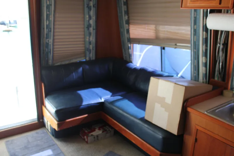 Slide: The Image of Interior of a 1994 Mikelson 64 yacht with blue leather seating and a cardboard box. - 12