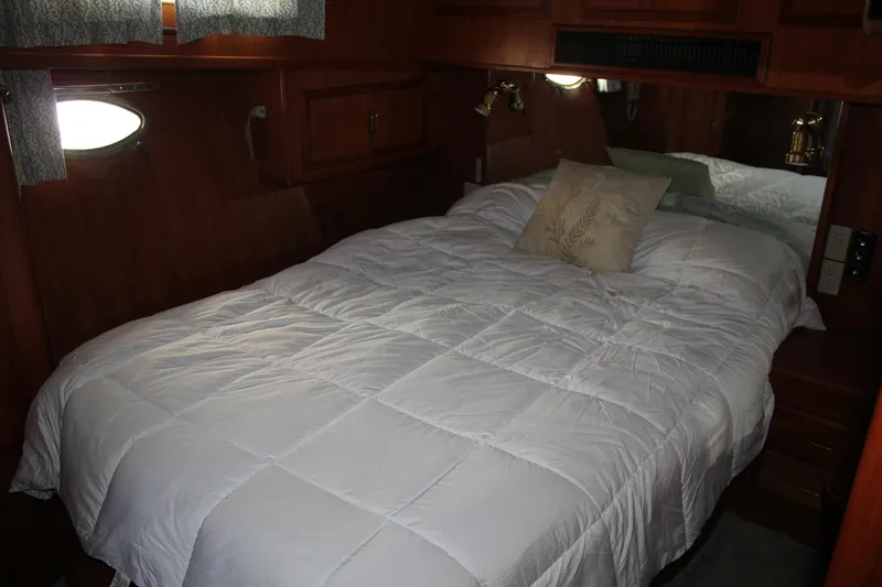 Slide: The Image of Cozy bedroom in a 1994 Mikelson 64 yacht with wooden interior and white bedding. - 14